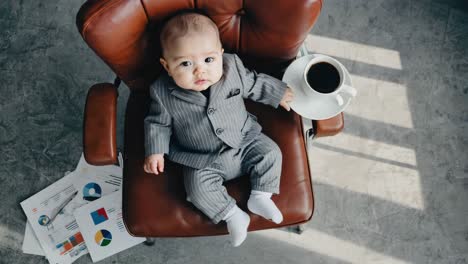 baby boss in a pinstripe suit sitting on an executive chair with coffee
