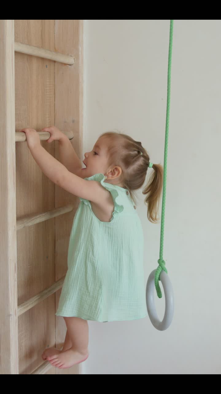 Happy Little Girl Climbing Wooden Wall Ladder Indoors