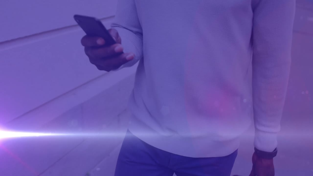 video de luces de colores sobre un hombre afroamericano caminando al trabajo, usando un teléfono inteligente en la calle