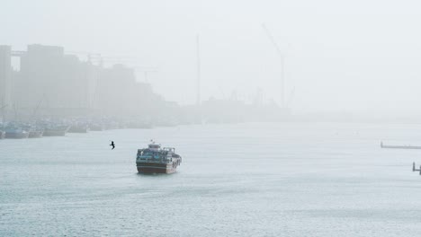 boat floating in the middle of dubai creek with deira port in misty background