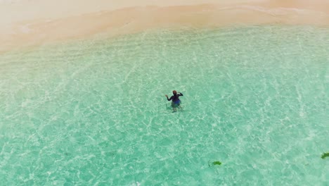 Amazing-aerial-footage-of-a-model-enjoying-the-beach-at-Petit-St-Vincent-with-a-yacht-sailing-by-in-the-background