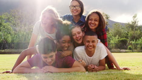 Group-of-teenage-friends-having-fun-lying-in-a-pile-on-grass