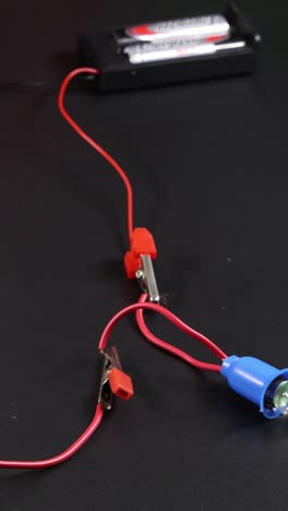 hands connect wires to test electric circuit