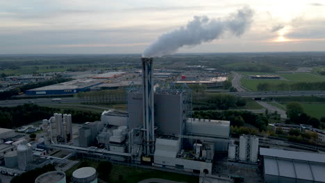 Antena-De-Chimenea-De-Fábrica-Humeante-Con-Un-área-Industrial-En-El-Fondo