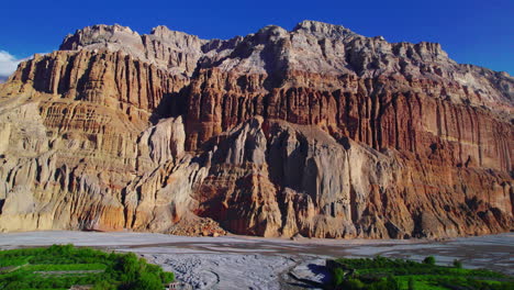 drone glides over unique dry mountains of chuksang in upper mustang, nepal. alluring video with a backdrop of blue sky and river. explore the captivating beauty of annapurna area