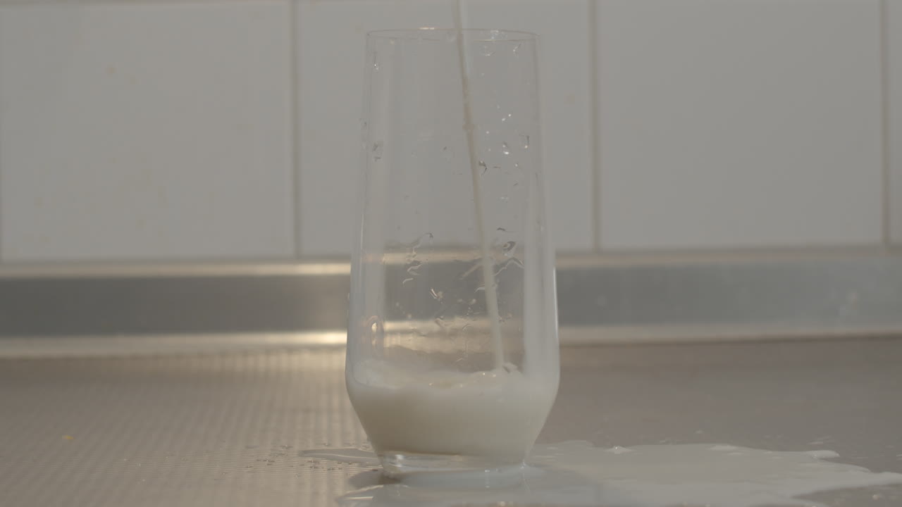 Leite sendo derramado na bancada da cozinha enquanto enche um copo