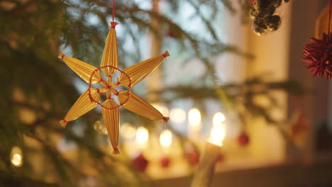 adornos navideños - estrella de paja colgando de un árbol de navidad, suecia, cerrar