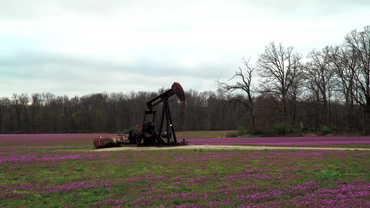 Oil field pump jack slowly pumping oil or natural gas out of the ground. 4K UHD Wide Shot