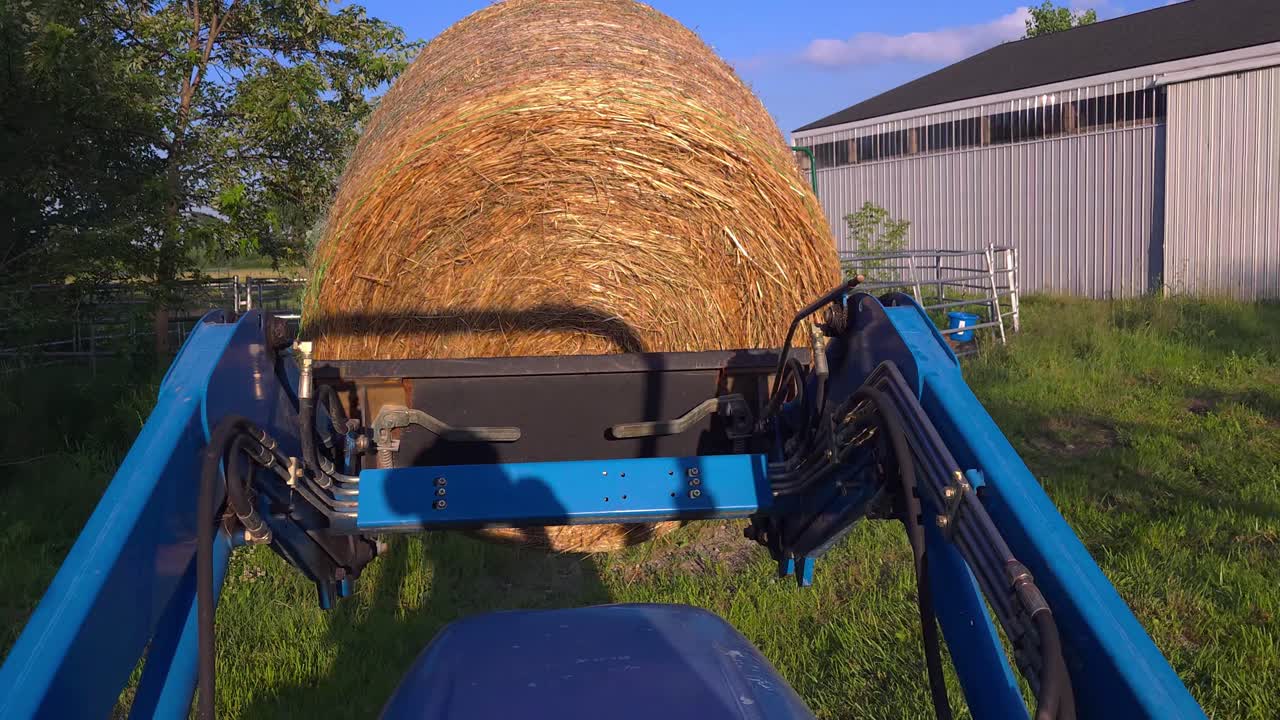 농부 는 시골 의 농장 에서 파란색 트랙터 를 사용 하여 큰  가루 를 옮기고 있다