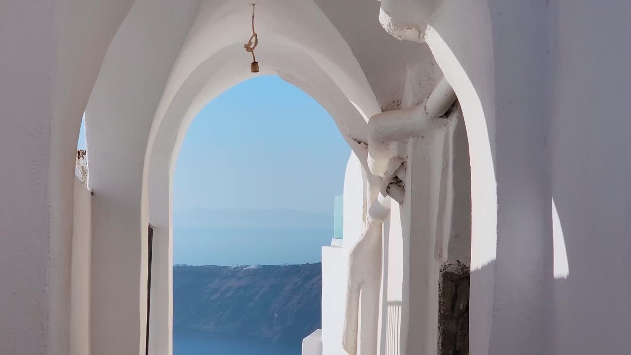 una mujer joven camina entre las casas para ver la vista del mar.