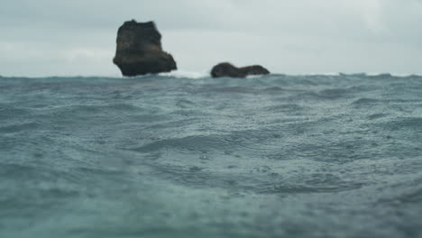 calm ocean surface with island cliffs in the distance under soft sky