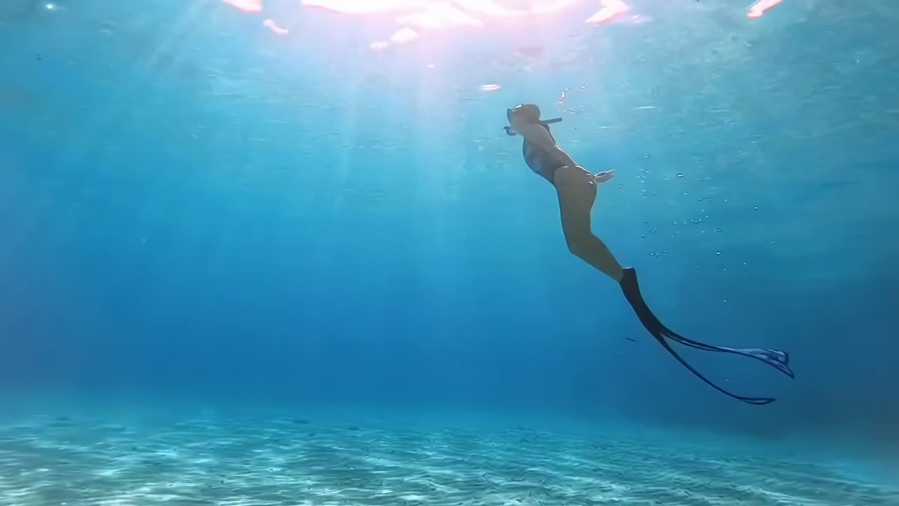 Underwater video of a diver swimming near coral, captured from a side angle, serene and clear