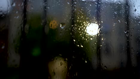 close up moody view of rain droplets on window covered with black bars in late afternoon