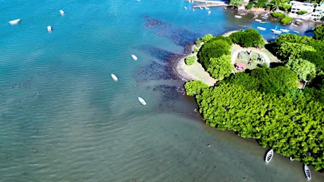 Aerial dolly across tropical water inlet and coastline near village in Mauritius with bright sea colors