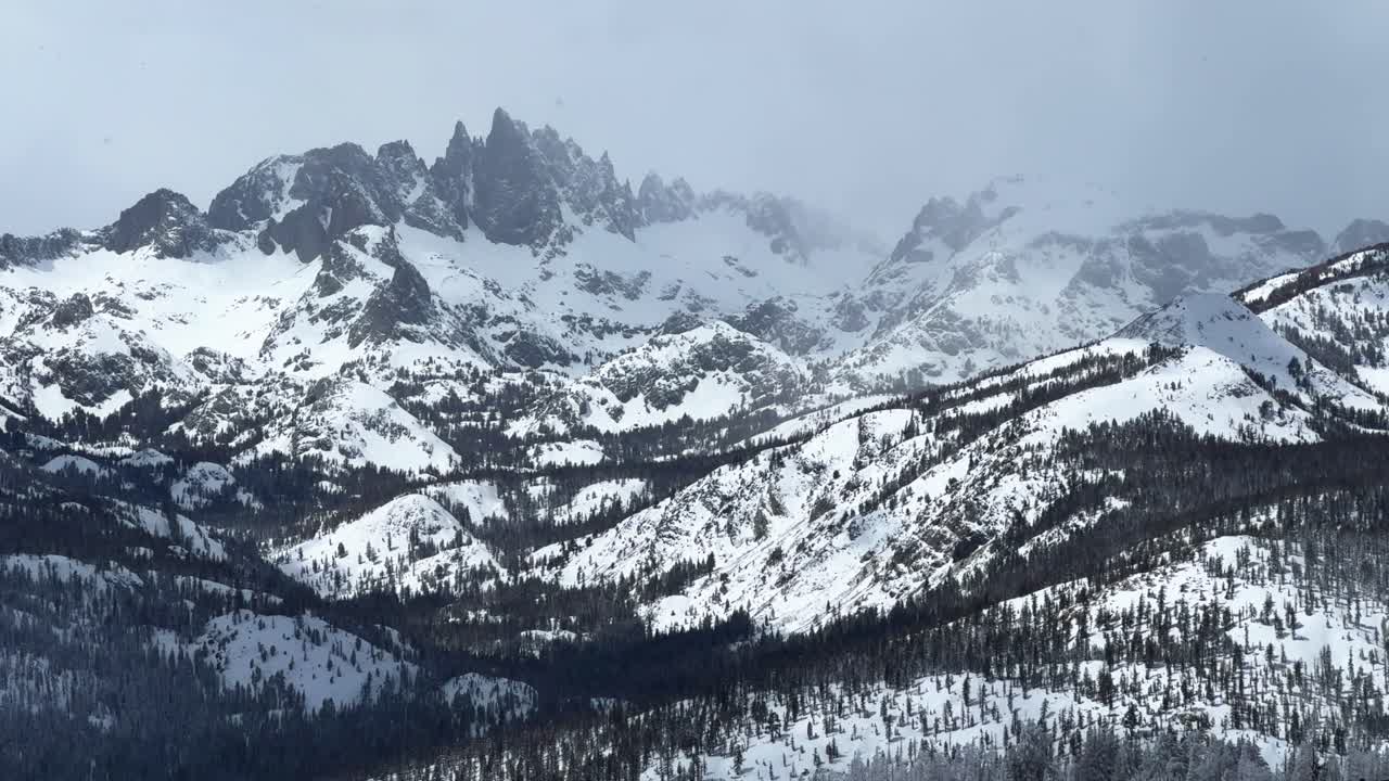 Los Hemlocks nevando en la estación de esquí Mammoth Mountain, California. Ventisca de invierno y primavera, nieve polvo profunda, niebla brumosa. Picos irregulares de Minaretes, vista panorámica, telesilla, nubes grises, místico y soleado. Acercamiento.