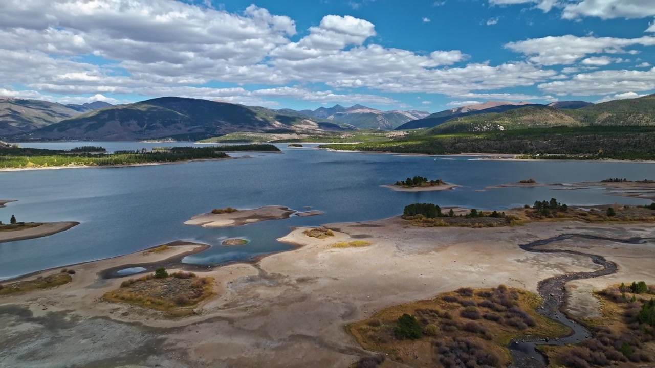 Panorama aéreo cênico de margens de lago baixas, áreas gramadas e montanha distante, Reservatório Dillon, Colorado