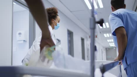diverse female and male doctors wearing face mask transporting patient