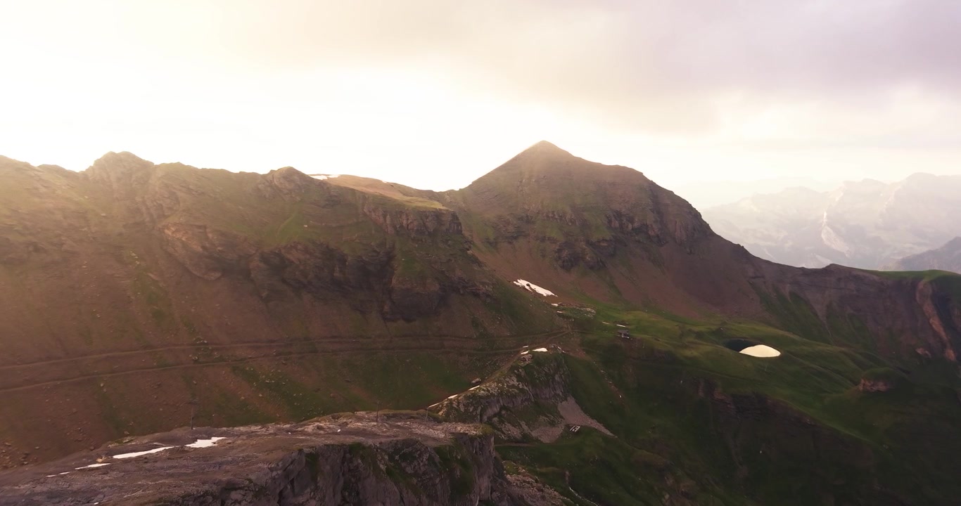 Drone-lento Schilthorn-vuorten yli, alppihuippujen, laaksojen ja maisemallisten auringonlaskunäkymien kera.