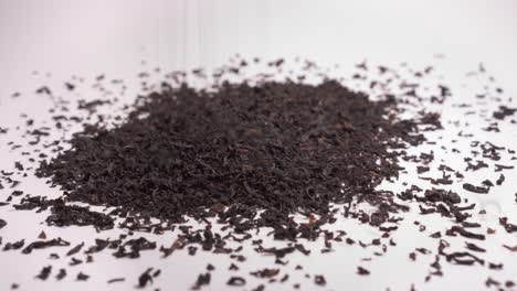 making a heap of dried black tea on white background - close up