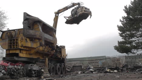 mechanical claw arm dropping crushed car scrap metal in breakers yard