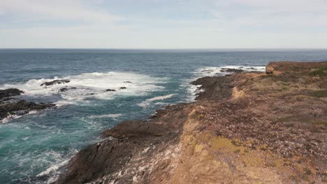 flying alongside a rocky, cliff laden shoreline. aerial