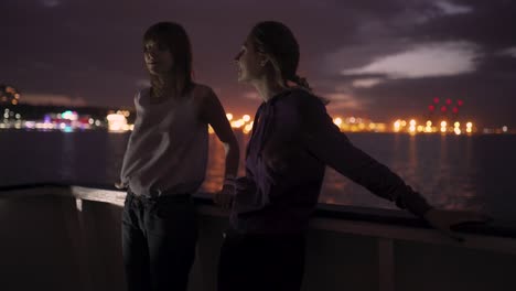silueta de dos atractivas mujeres jóvenes que viajan en un barco por la noche. amigas en el barco