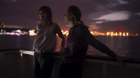 silhouette of two attractive young women traveling on a ship at night. girlfriends on the boat