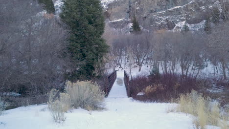 Punto-De-Vista-Caminando-Hacia-Un-Puente-En-Un-Camino-Cubierto-De-Nieve-En-El-Desierto