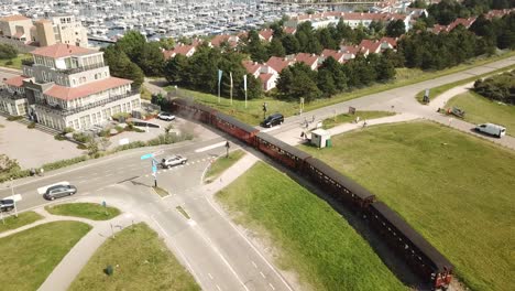 Historical-steam-engine-tram-crossing-a-road-and-arriving-in-little-town-Ouddorp,-netherlands