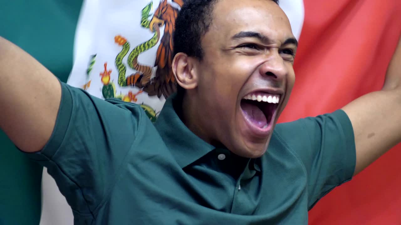 fanático mexicano celebrando mientras sostiene la bandera de méxico en cámara lenta