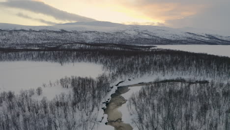 Luftaufnahme-über-Dramatischen-Skandinavischen-Sonnenaufgangsbergen-Mit-Malerischer,-Schneebedeckter-Waldsee-Wildnis