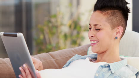 Pregnant-woman-lying-on-the-couch-while-using-tablet