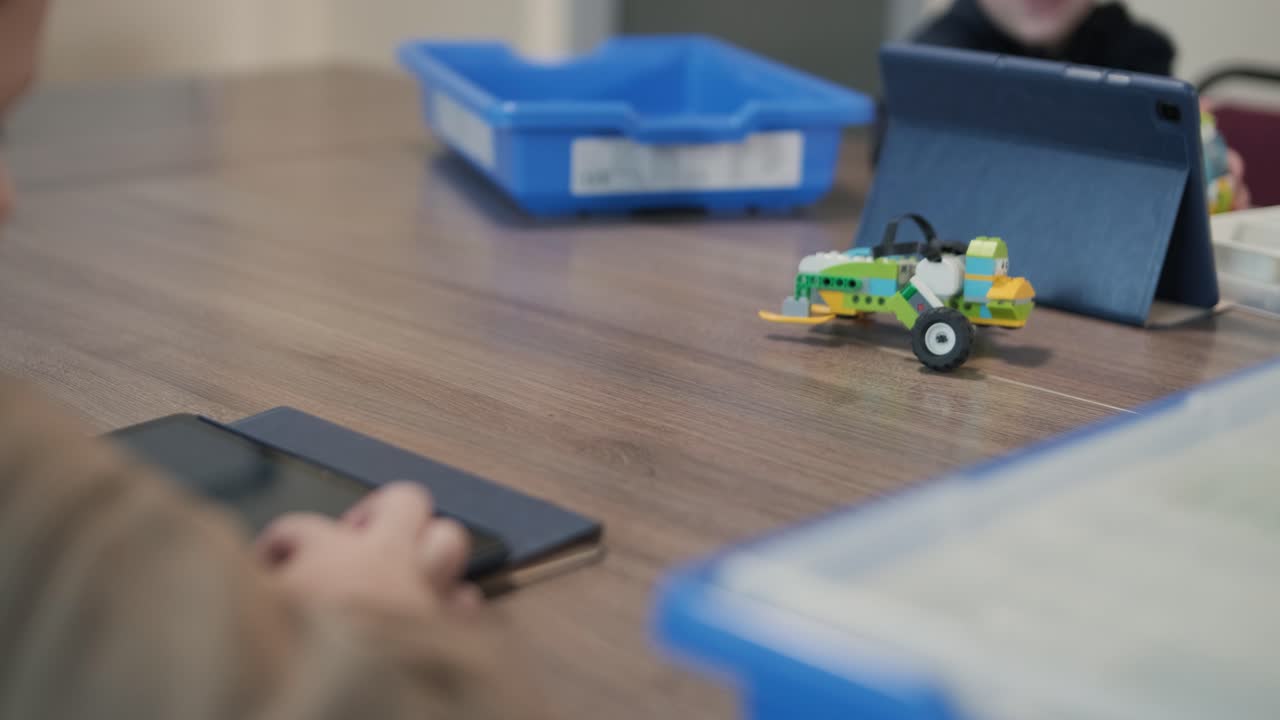 i bambini si sono concentrati attentamente sull'assemblaggio di parti da un kit di robotica, con un tablet che mostra le istruzioni, promuovendo l'apprendimento e la creatività