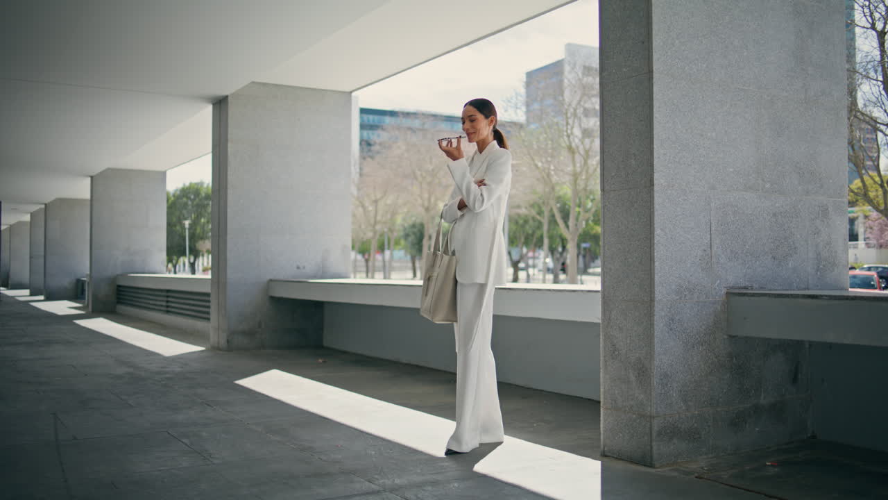 성공한 소녀는 현대적인 건물 주차장에 서서 스피커 전화를 하고 있습니다.