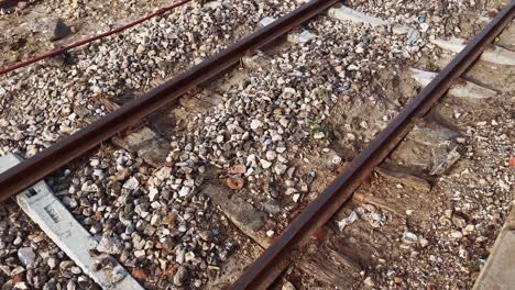 close up of weathered railway tracks covered in gravel and littered with garbage at ghotki railway station, highlighting the poor maintenance and environmental pollution