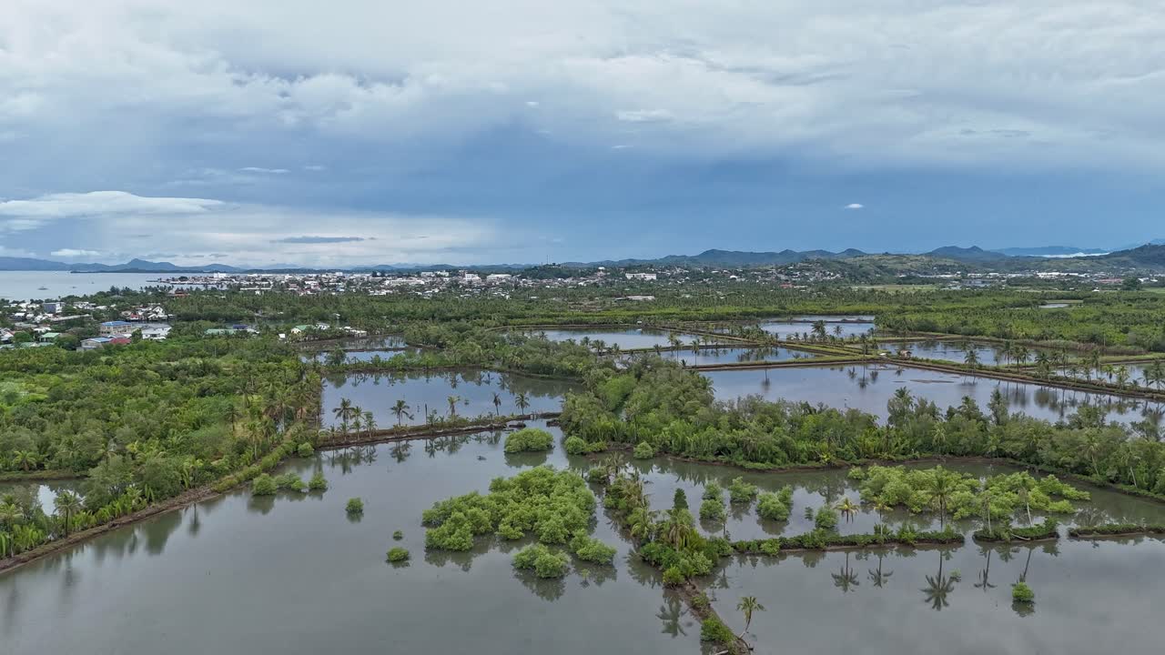 Drone view over shrimp ponds surrounded by lush greenery in Sabang under a cloudy sky