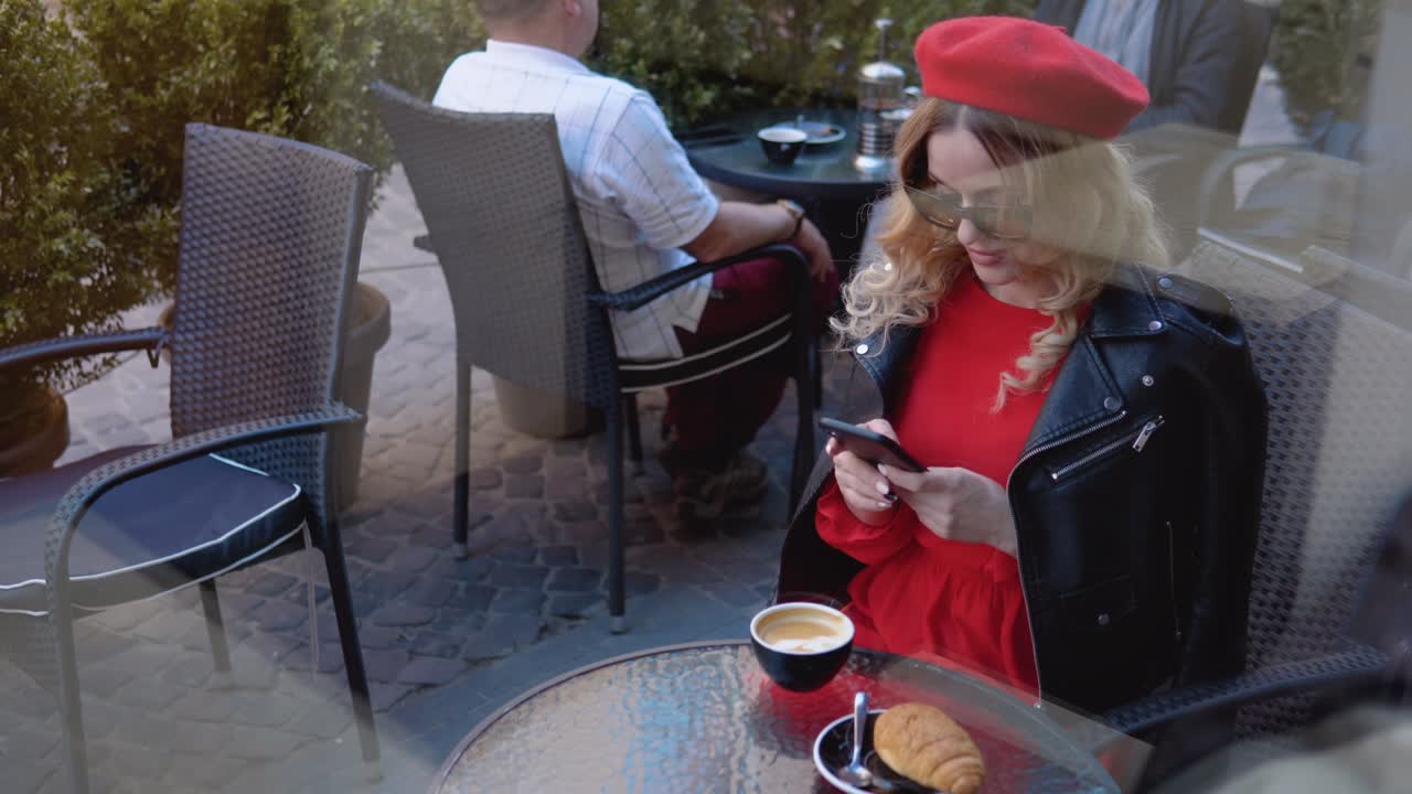 Coffee break with croissant. Modern urban young woman working online on cell phone on cozy restaurant terrace