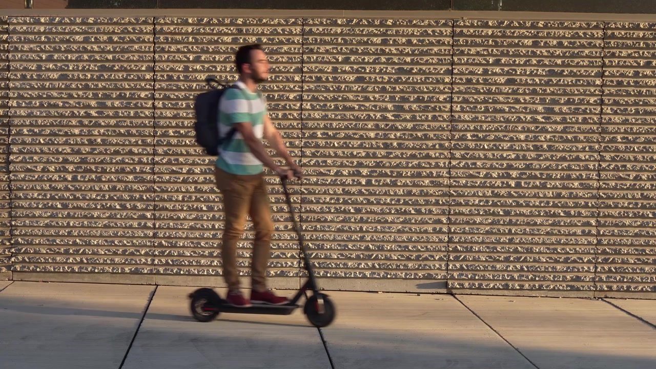 Dos personas en patinete eléctrico con un fondo urbano.