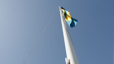 Hombre-Levantando-La-Bandera-Sueca-En-El-Asta-De-La-Bandera-En-Cámara-Lenta,-Día-De-Verano