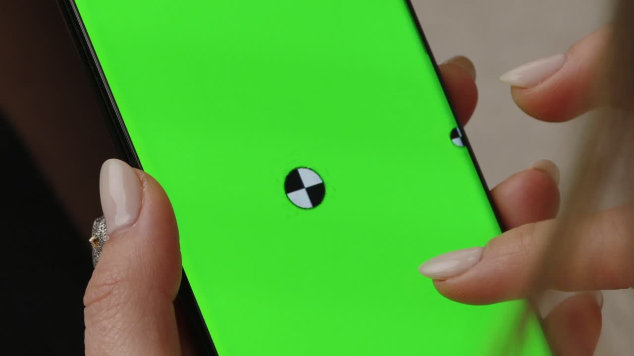 Close up of hand interacting with a smartphone displaying a green screen