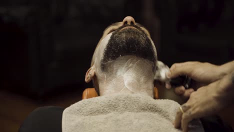 barber putting shaving cream on his client in the barber shop - close up