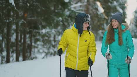 loving man and woman in slow motion winter skiing in the woods looking at each other smiling. valentine day