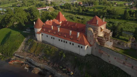 slow aerial over bauska castle reconstruction and ruins with scaffolding in latvia