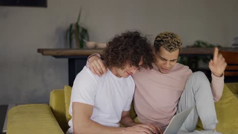 two male gay couple embraced using laptop surfing internet together for fun