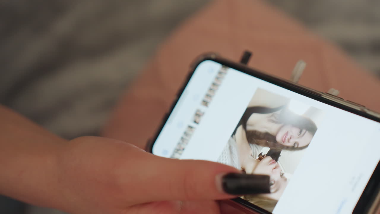 CloseUp Thumbnail Gallery Showing Caucasian Editor Curating Portraits On Smartphone, Methodical Swipes, Black Nails Tapping, Organizing Portfolio And Approving Aesthetic Sequence In Low Light
