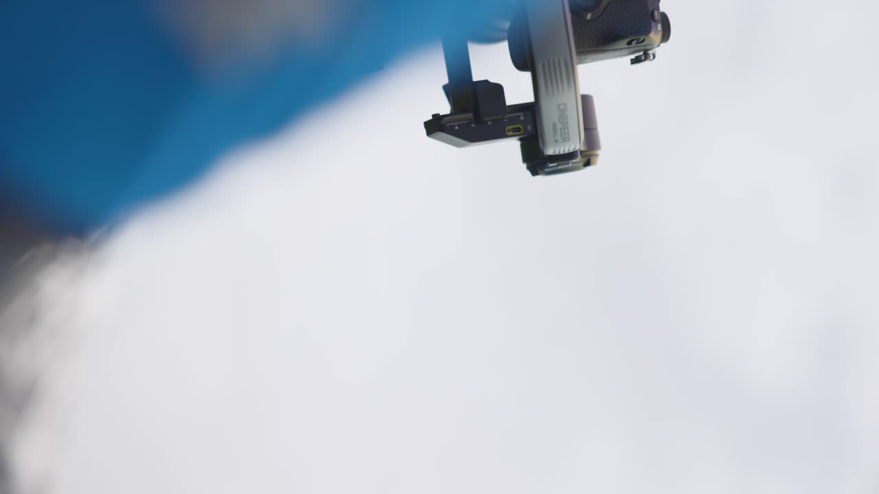 사람이 들고 있는 발 안정 장치에 장착된 카메라의 클로즈업, 야외 환경에서 부드럽고 전문적인 비디오 영상을 찍는