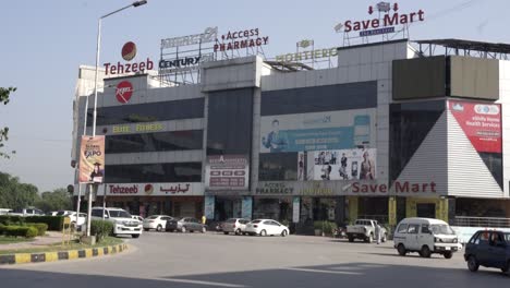 photographing a prominent commercial building located on the main road, surrounded by cars, with a clear blue sky above.