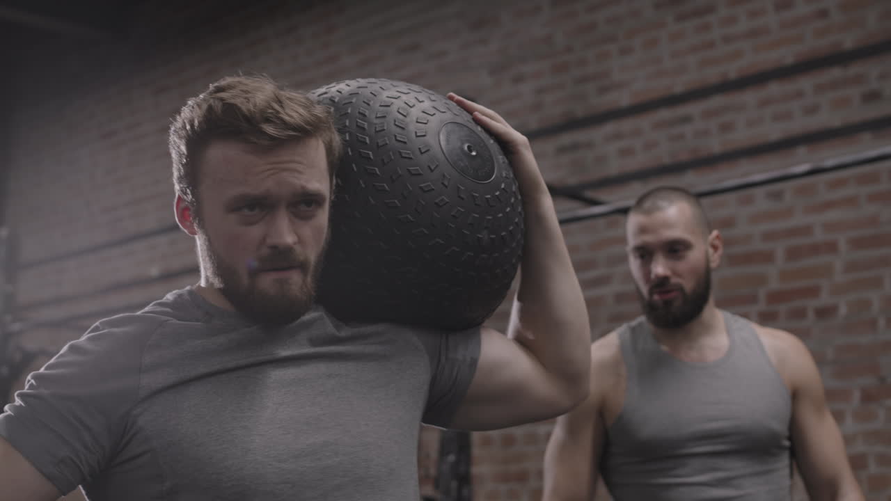 Sportsman Carrying Heavy Rubber Ball in Gym