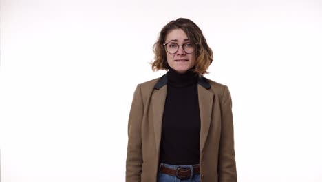 caucasian young woman in brown jacket looking sad and scary isolated on white background in studio. holding hands close to the face in fear. people sincere emotions, lifestyle concept