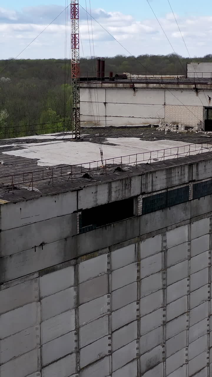 Ruined large building of a factory on green nature background. Old industrial plant with abandoned building. Abandoned factory. Vertical video